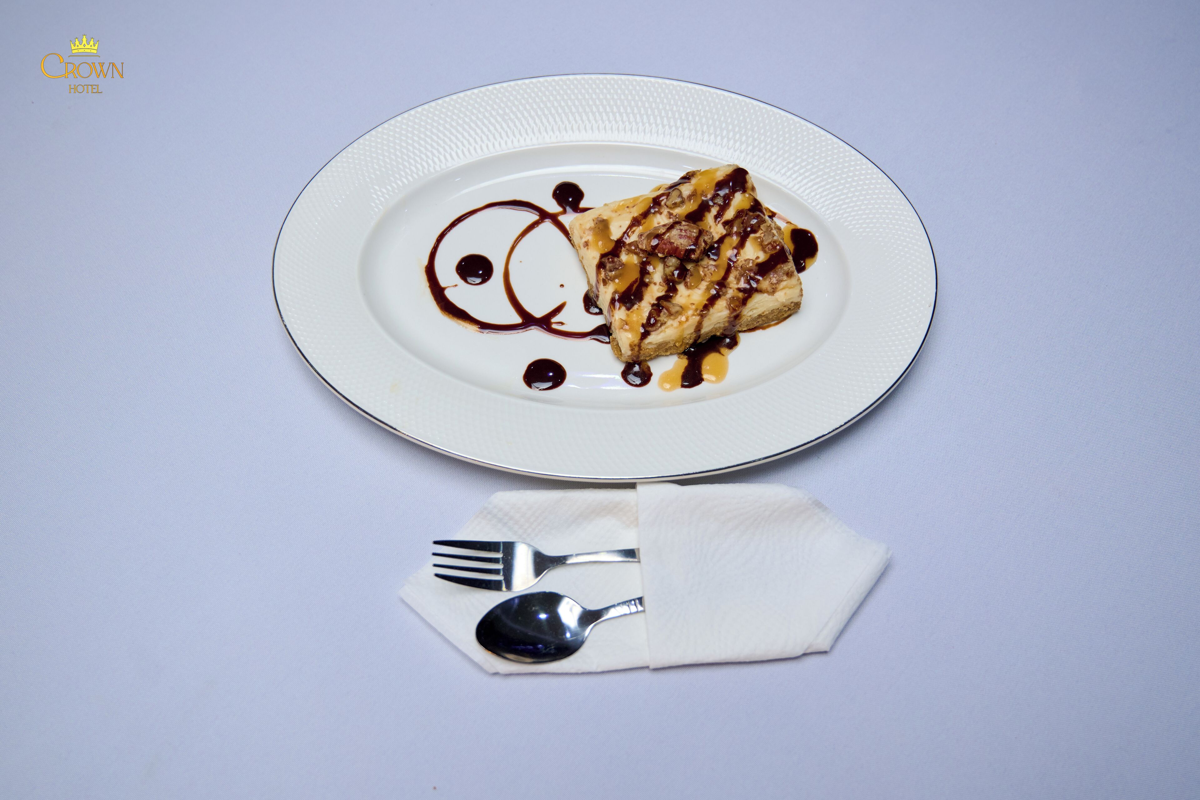 A plate with a dessert, a fork, and a spoon on a napkin.
