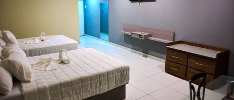 A hotel room with two beds, a wooden dresser, a TV mounted on the wall, and a glass table.
