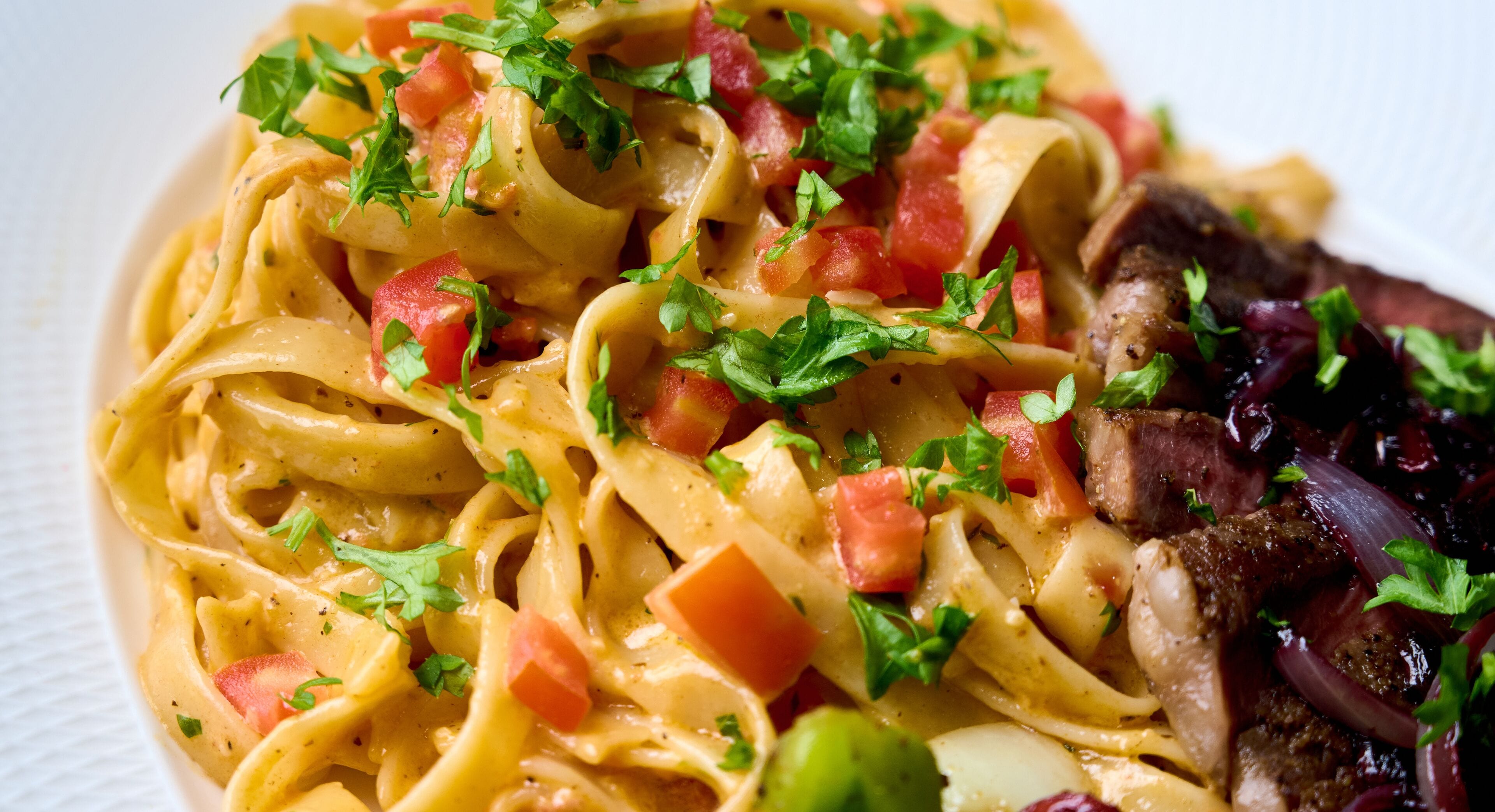 Une assiette de pâtes, de la viande et des légumes.