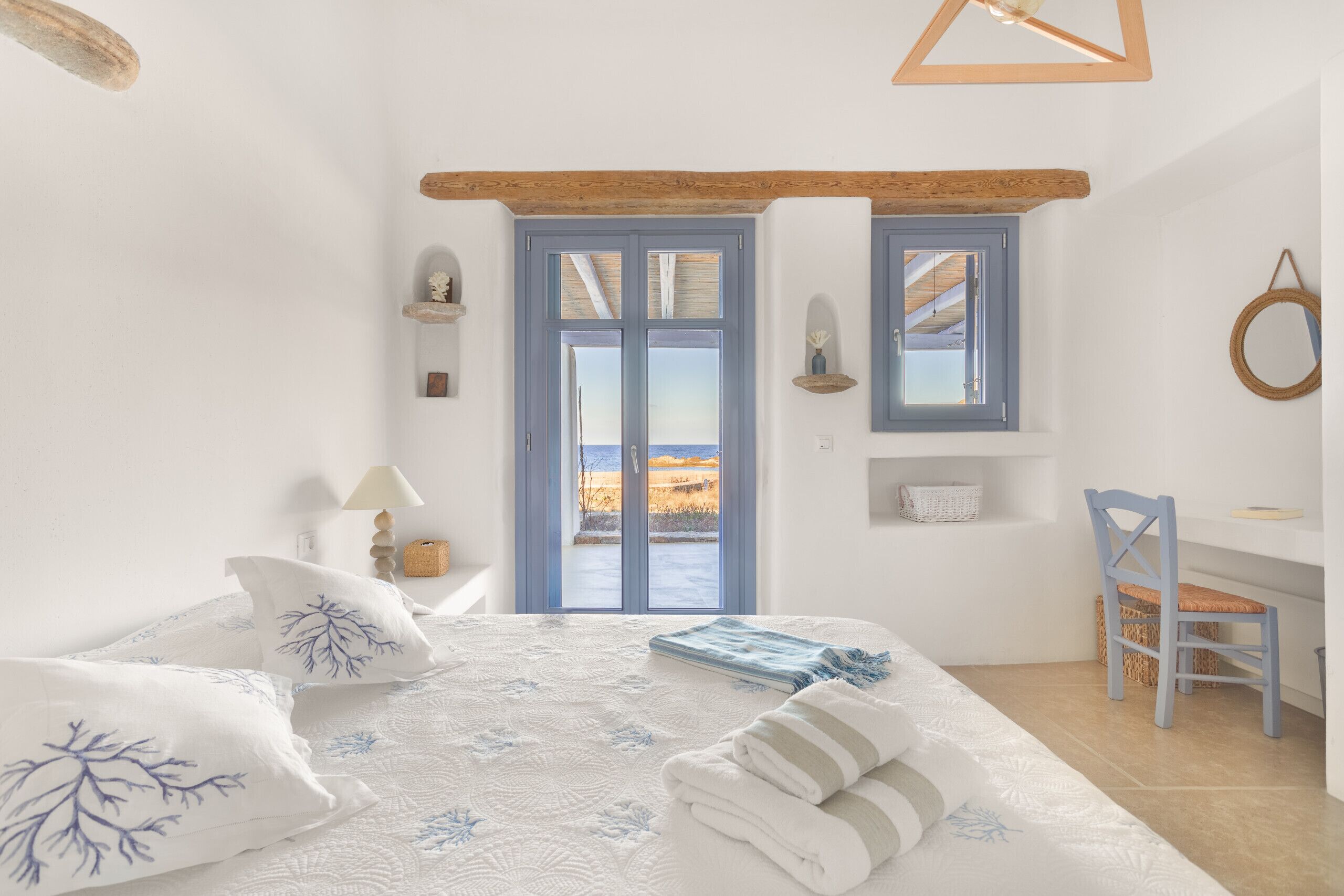 Une chambre à coucher avec un lit, un bureau, une chaise, une fenêtre donnant sur un paysage agréable et une porte.