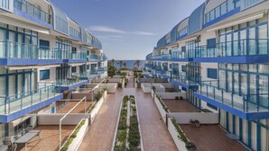 A modern hotel with multiple balconies, a central courtyard with plants, and a view of the sea. - RentitSpain Castell Beach, Views, and Parking (Castell de Ferro)