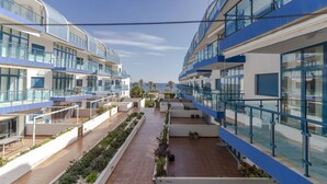 A modern hotel with multiple balconies, a central courtyard with plants, and a view of the sea. - RentitSpain Castell Beach, Views, and Parking (Castell de Ferro)