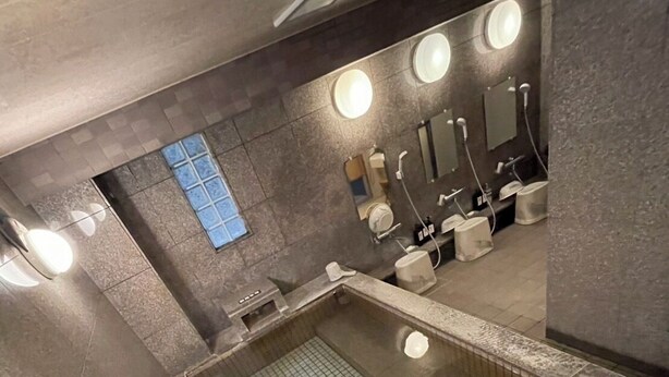 Un baño moderno con una amplia piscina azulejada, varios lavamanos e iluminación empotrada.
