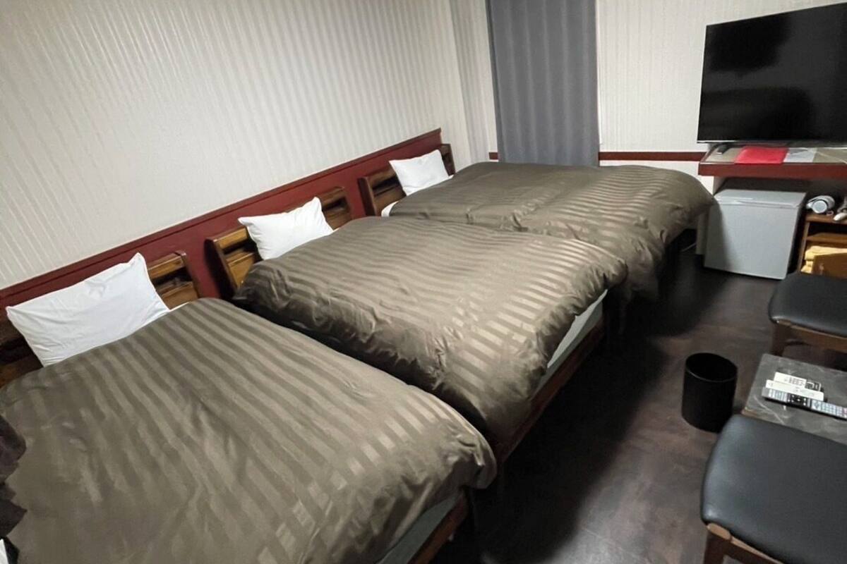 Una habitación de hotel con dos camas, televisión, escritorio y una silla.