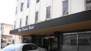 Un hotel con un letrero que dice "Mats Daichi Hotel" y un coche blanco estacionado adelante.