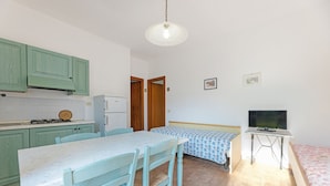 Una cocina compacta con comedor, un televisor pequeño y una cama.