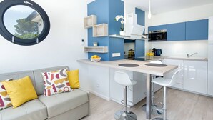 A modern kitchen with blue cabinets, a round window, and a dining area with two bar stools. - Californian style pool villa for 10 people with air conditioning (ST AYGULF)