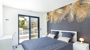 A modern bedroom with a large bed, a nightstand, and a view of the outside balcony. - Californian style pool villa for 10 people with air conditioning (ST AYGULF)