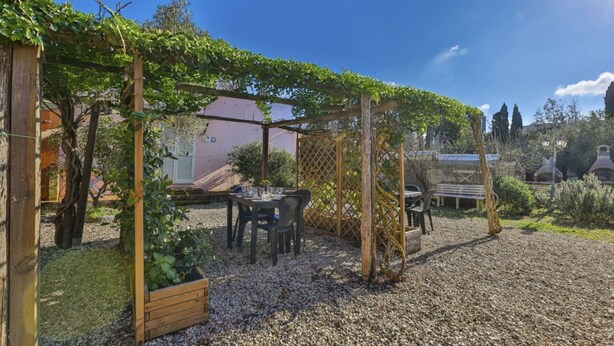 A garden with a pergola covered in vines, a table with chairs, and a bench. - APPARTAMENTI LE PRADE - LE PRADE BILO 2 (Portoferraio)