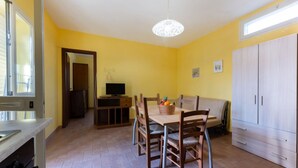A dining area with a table and chairs, a television, and a cabinet. - APPARTAMENTI LE PRADE - LE PRADE BILO 2 (Portoferraio)