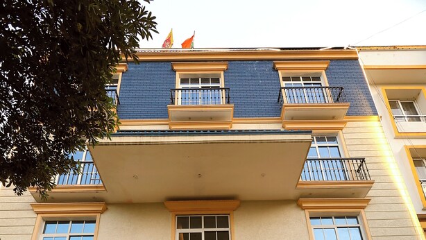 A multi-story building with balconies, a gated entrance, and steps leading to the door. - The Blue Vista Hotel (Greater Noida)