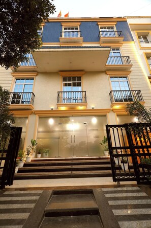 A multi-story building with balconies, a gated entrance, and steps leading to the door. - The Blue Vista Hotel (Greater Noida)