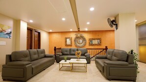 A living room with two sofas, a coffee table, and a decorative mirror on the wall. - The Blue Vista Hotel (Greater Noida)