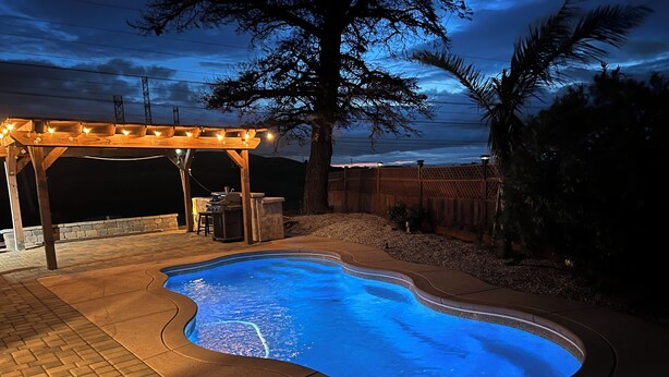 A swimming pool with a wooden deck and a pergola with string lights. - 3-bedroom Charming Home in the Hills of Pittsburg with hillside view & pool (Pittsburg)