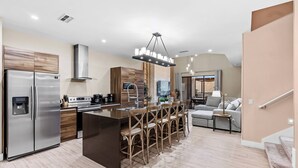 A modern kitchen with a central island, stainless steel appliances, and a bar stool seating arrangement. - 4BR house with private hot tub in kissimmee (Kissimmee)