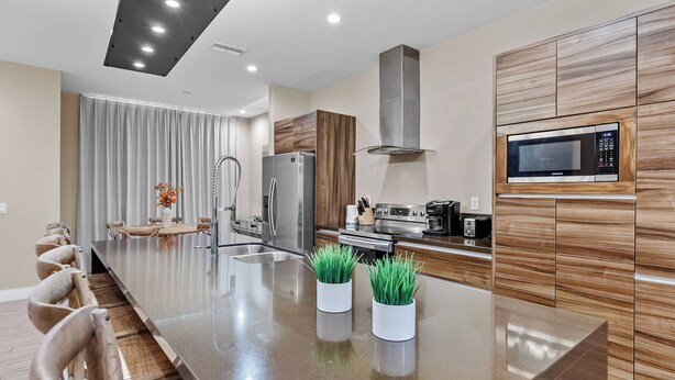 A modern kitchen with a central island, stainless steel appliances, and wooden cabinetry. - 4BR house with private hot tub in kissimmee (Kissimmee)