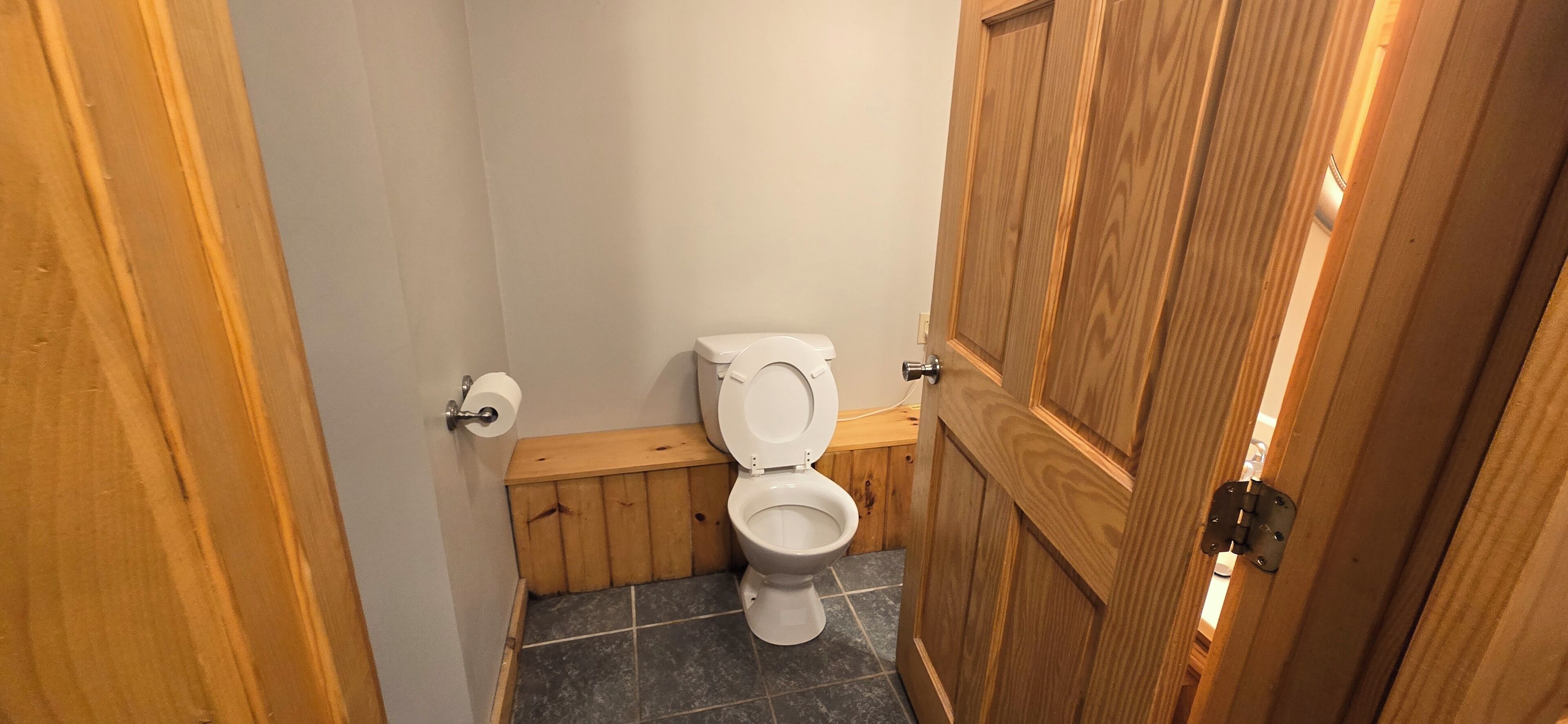 A small bathroom with a wooden toilet and a wooden cabinet.