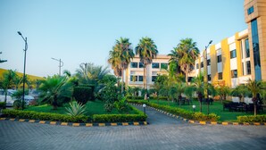 A modern building with a yellow facade, surrounded by well-maintained greenery and palm trees. - Bodhi Redsun – Gateway to Lumbini, Comfort in Bhairahawa (Basantapur)