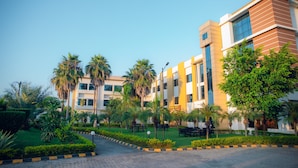 A modern building with multiple floors, surrounded by well-maintained greenery and palm trees. - Bodhi Redsun – Gateway to Lumbini, Comfort in Bhairahawa (Basantapur)