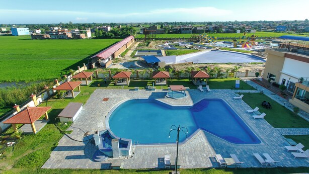 A swimming pool with a heart-shaped design, surrounded by lounge chairs and covered areas. - Bodhi Redsun – Gateway to Lumbini, Comfort in Bhairahawa (Basantapur)
