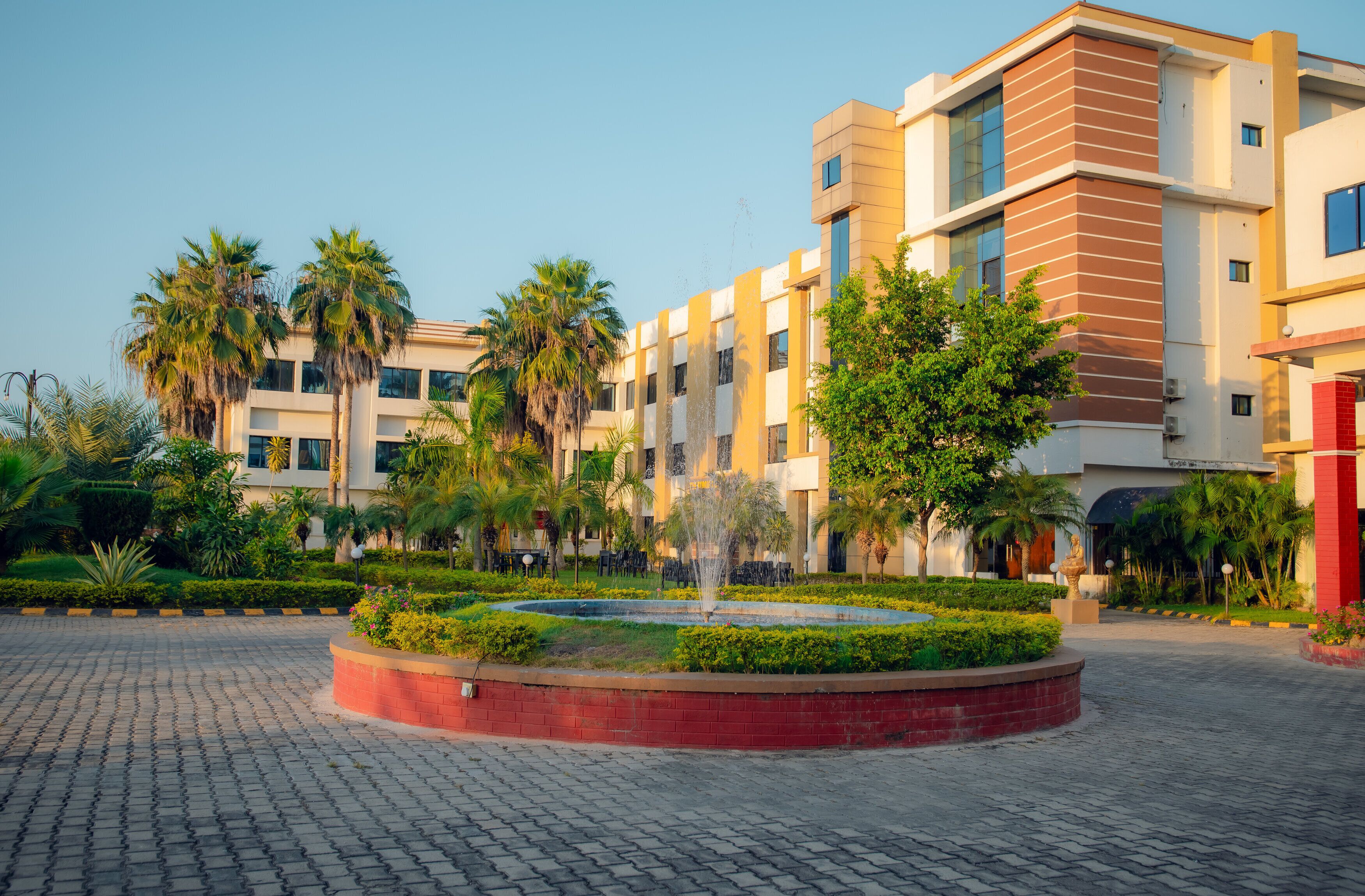 A modern building with a courtyard, palm trees, and a fountain.