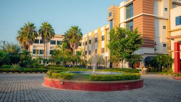 A modern building with a courtyard, palm trees, and a fountain.