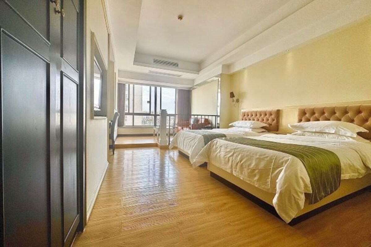 A hotel room with two beds, a balcony, and a view of the city.