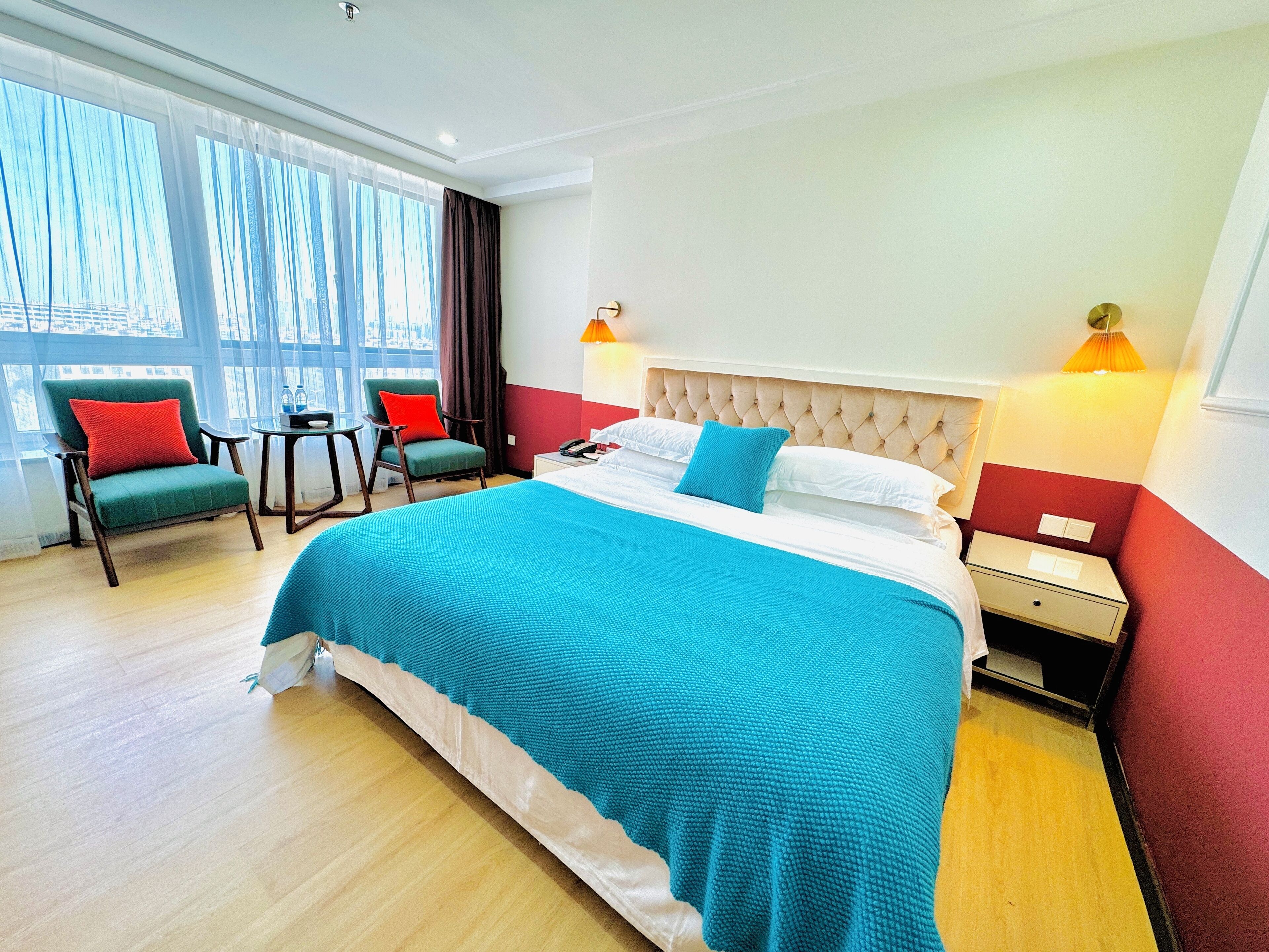 A hotel room with a large bed, two chairs, a small table, and a nightstand.