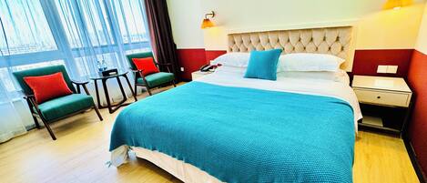 Una habitación de hotel con una cama grande, un escritorio, dos sillas y una ventana con cortinas.