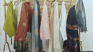 Um cabideiro com diversas peças de roupa penduradas.