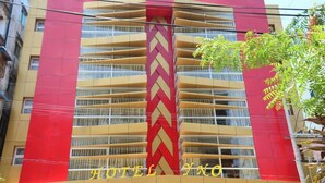 Een hotelgebouw met een opvallende rode en gele gevel, meerdere balkons en de naam 'HOTEL NO' zichtbaar.