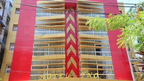 A hotel building with a prominent red and yellow facade, multiple balconies, and the name 'HOTEL NO' visible. - Hotel YNO (Yangon)