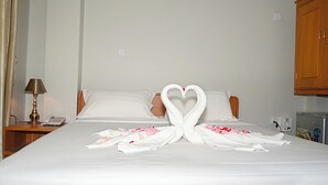 A hotel room with a neatly made bed, a bedside telephone, and a wooden cabinet. - Hotel YNO (Yangon)