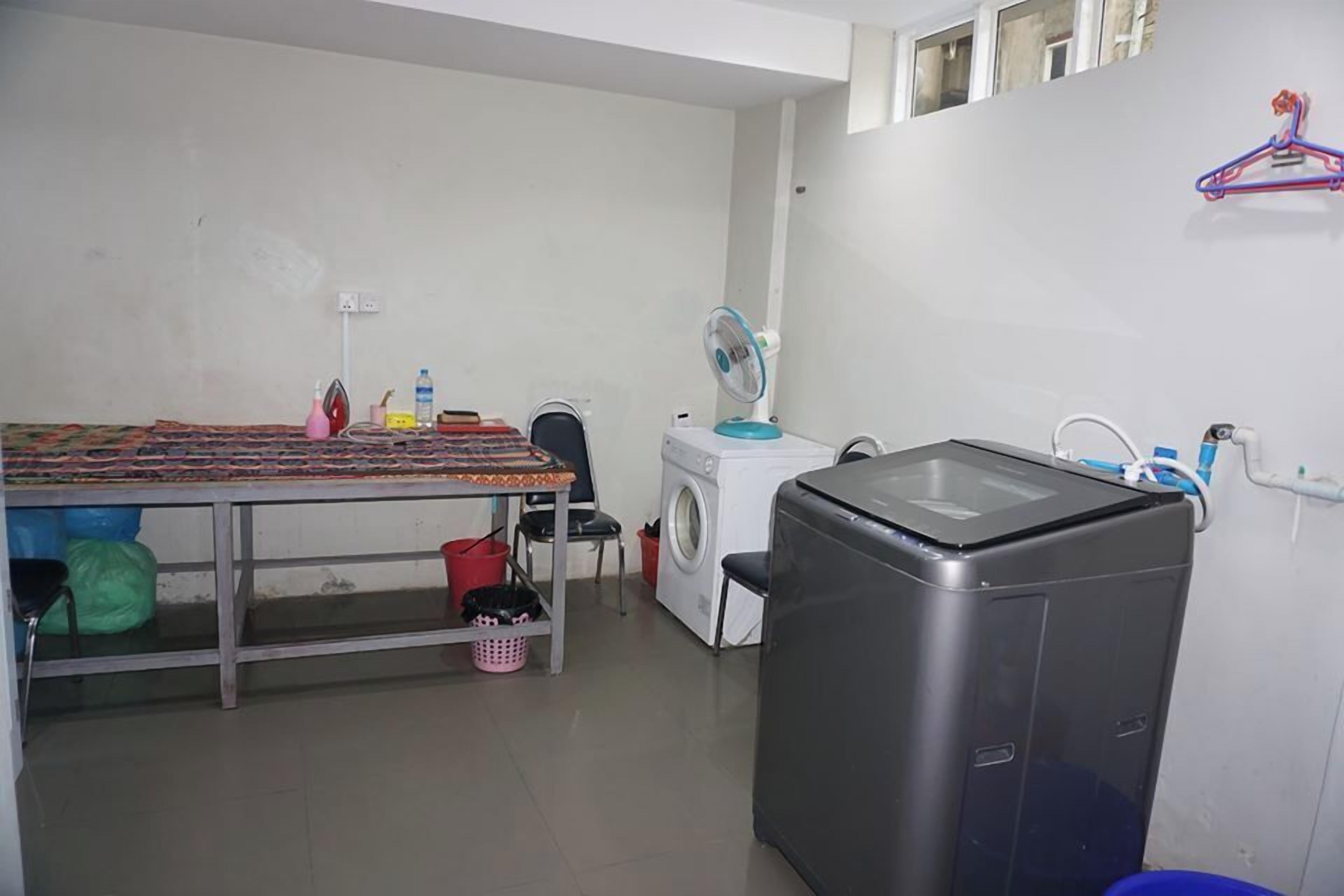 A laundry room with a table, washing machine, dryer, and a small refrigerator.