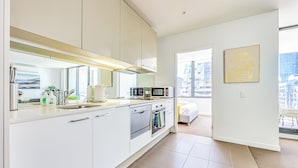 Eine moderne Küche mit weißen Schränken, Edelstahlgeräten und einem großen Fenster mit Blick auf die Stadt.