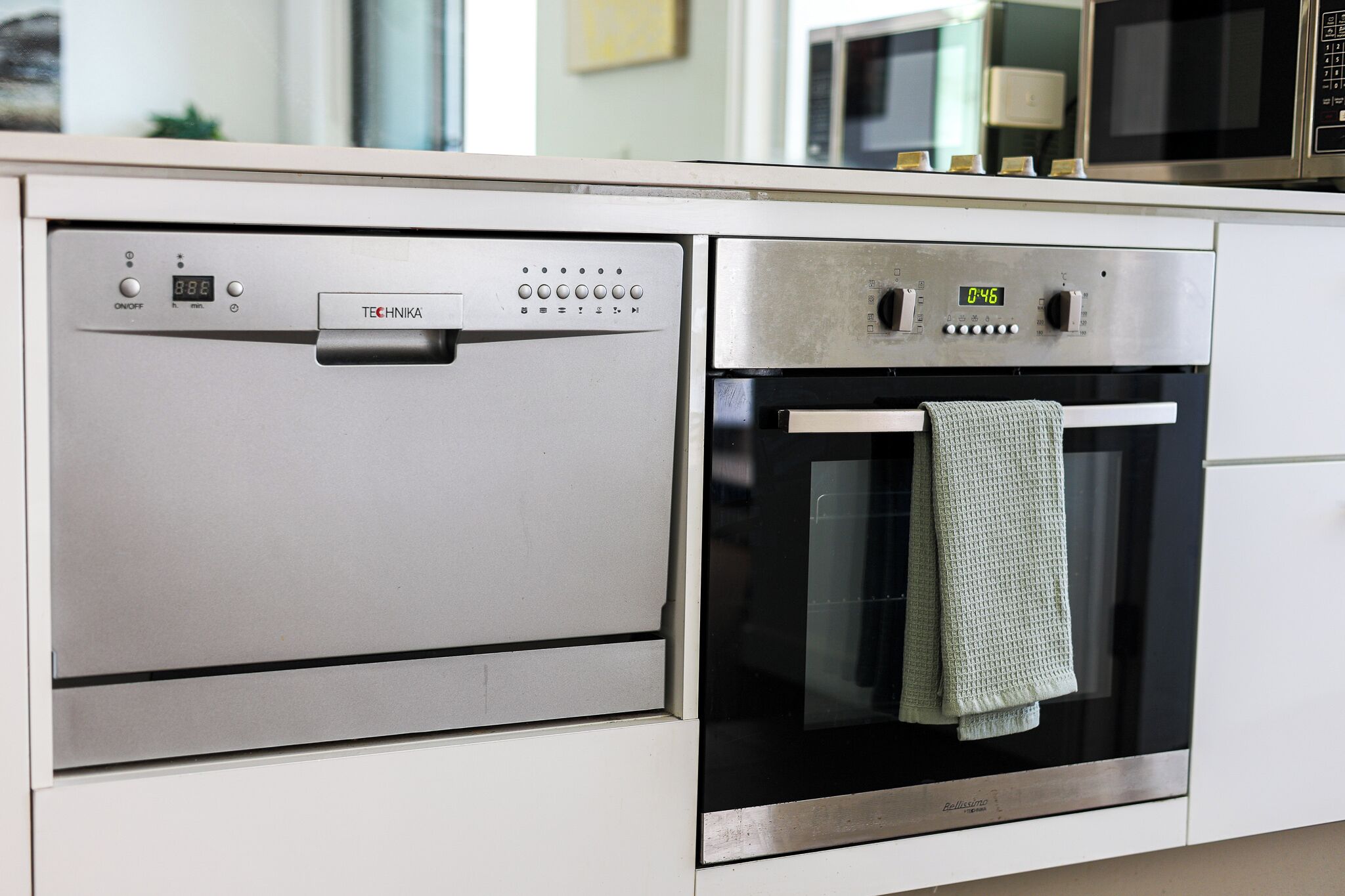 A kitchen with a dishwasher and oven, both with digital displays.