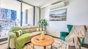 Ein modernes Wohnzimmer mit einer Couch, einem grünen Sessel, einem Couchtisch und einer Pflanze.