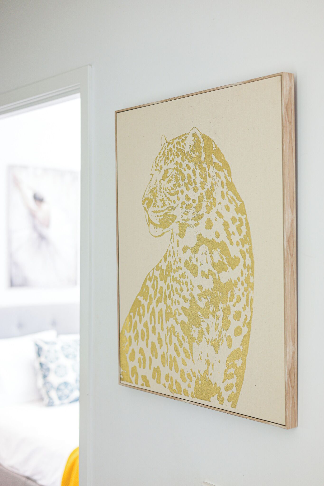 Una obra d'art emmarcada amb un lleopard penja d'una paret blanca.
