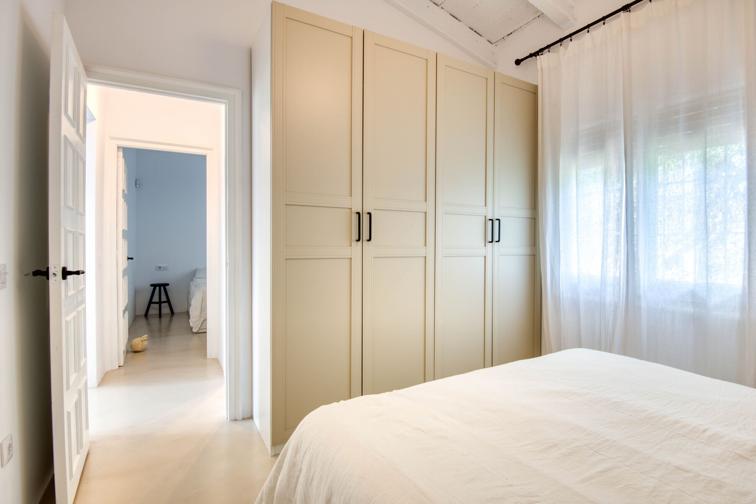 Un dormitorio con una cama grande, un armario y una puerta que da a otra habitación.