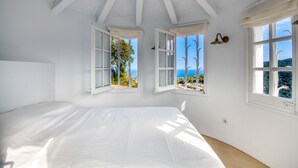 A bedroom with a large bed, two windows with open shutters, and a view of the sea. - CALMA: Spectacular holiday rental villa with private pool and sea views in Sa Riera, Begur. (Begur)
