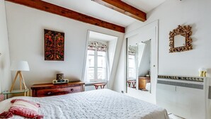Ein Schlafzimmer mit Bett, Kommode, Lampe, Spiegel und Heizkörper.