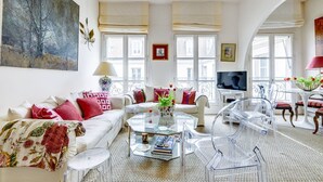 Ein geräumiges Wohnzimmer mit einem weißen Sofa, einem gläsernen Couchtisch und einem Fernseher.