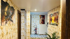 A hallway with patterned wallpaper, a fire extinguisher, and artwork on the walls. - Gulmohar guest house (Balasore)