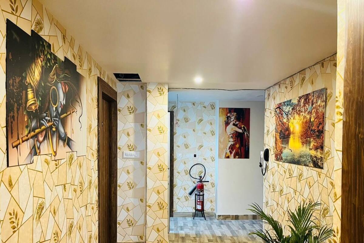 Un couloir avec un papier peint à motifs, un extincteur et des œuvres d’art accrochées aux murs.