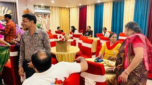 A banquet hall with round tables, red and white tablecloths, and guests seated. - Gulmohar guest house (Balasore)