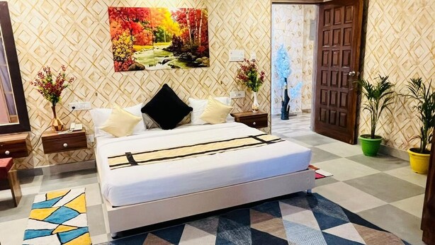 A bedroom with a bed, nightstands, a painting, and a patterned floor. - Gulmohar guest house (Balasore)