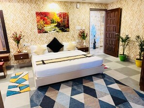 A bedroom with a bed, nightstands, a painting, and a patterned floor. - Gulmohar guest house (Balasore)
