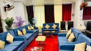 A living room with blue sofas, a red carpet, and a Buddha statue. - Gulmohar guest house (Balasore)
