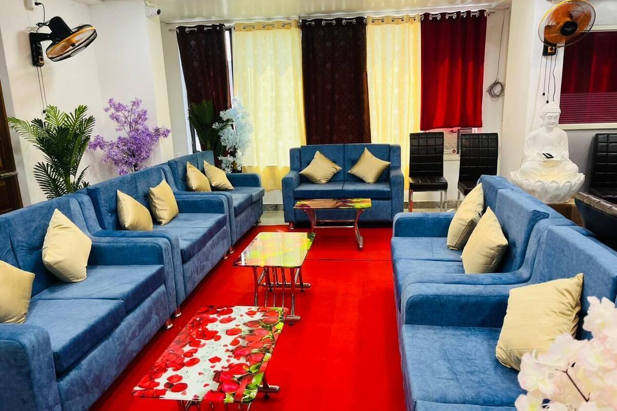 Un salon avec des canapés bleus, une moquette rouge et une statue de Bouddha.