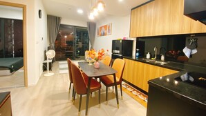 A modern kitchen with wooden cabinets, a black countertop, and a dining area with a table and chairs.